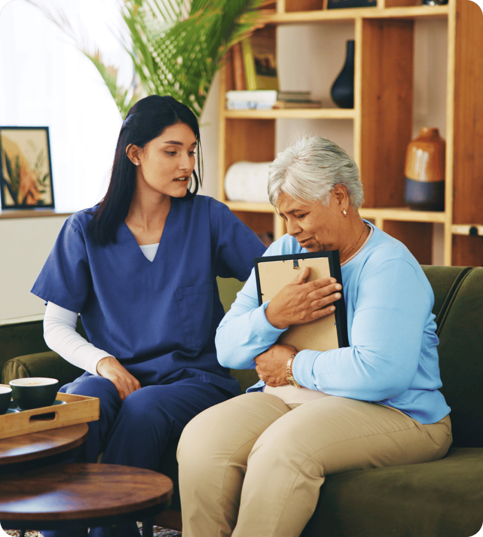 Healthcare worker assisting older woman in living room